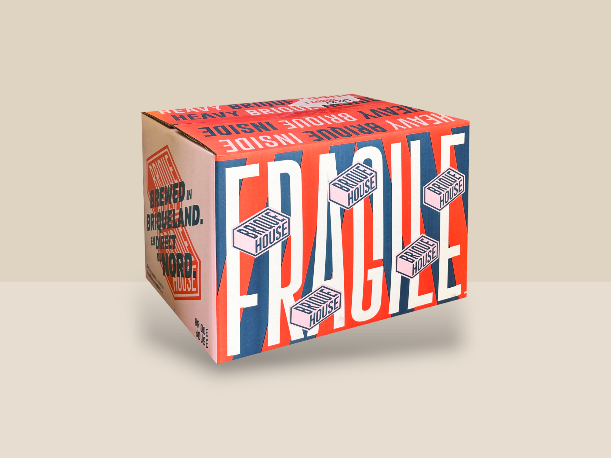 Une caisse rouge, blanche et bleue avec des briques roses et l’inscription fragile en grand sur la face avant.