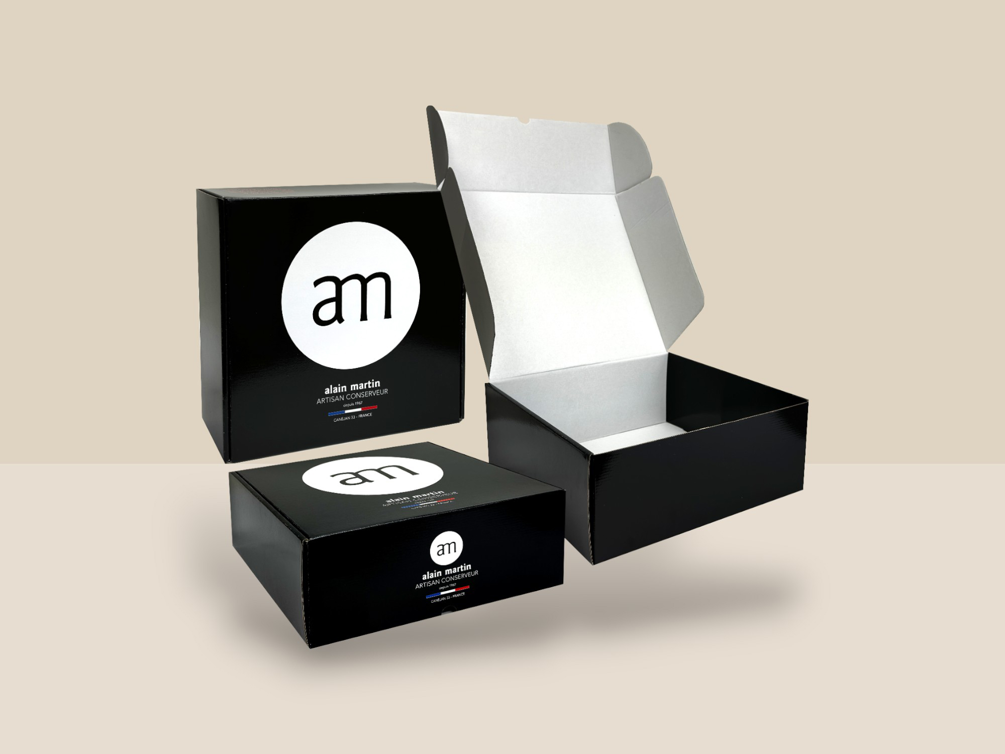 L'image montre une boîte en carton noir au design moderne et sobre. Sur la face avant et le dessus de la boîte, il y a un grand cercle blanc avec le logo 